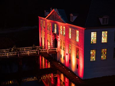 Die historische Schlossanlage von Dornum im Dunkeln, beleuchtet für den Weihnachtsmarkt