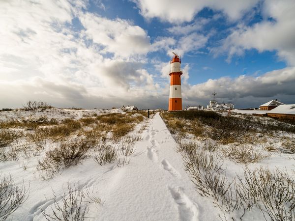 Leuchtturm inmitten der verschneiten Dünen auf Borkum