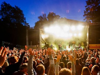 Mitsingende Menschenmenge vor der erleuchteten Bühne bei Dämmerung